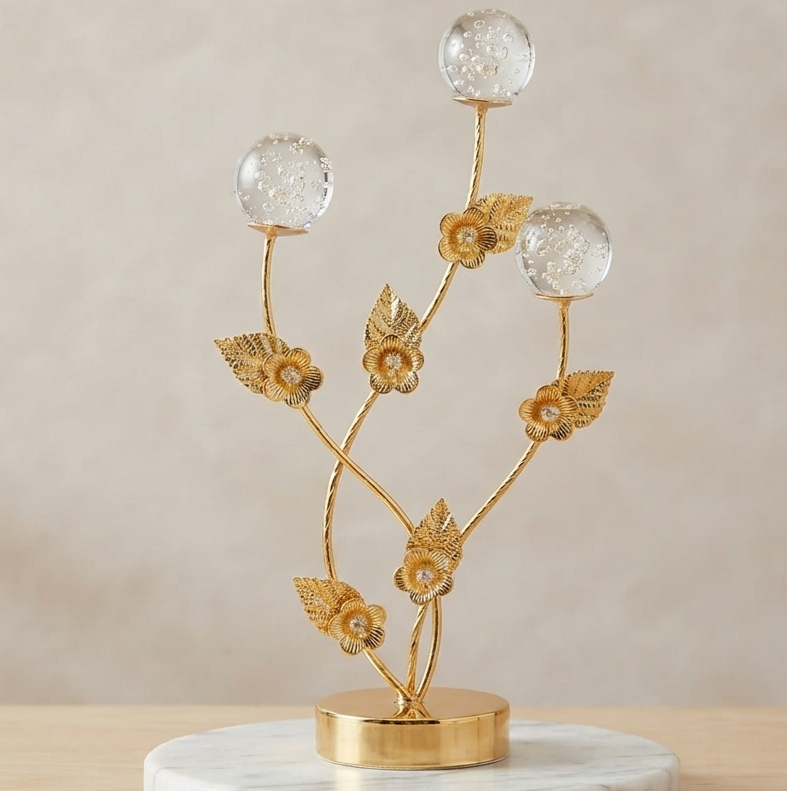 Golden decorative flower branch showpiece with crystal bubble spheres on a clean neutral background.