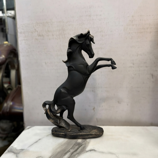 A high-resolution, clean product photo of the matte black rearing horse statue with bronze highlights on its mane and base, standing on a white marble surface. The orange sticker has been removed.