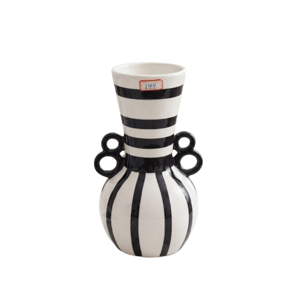 Black and white striped ceramic decorative vase with dual ring handles on a white marble surface.