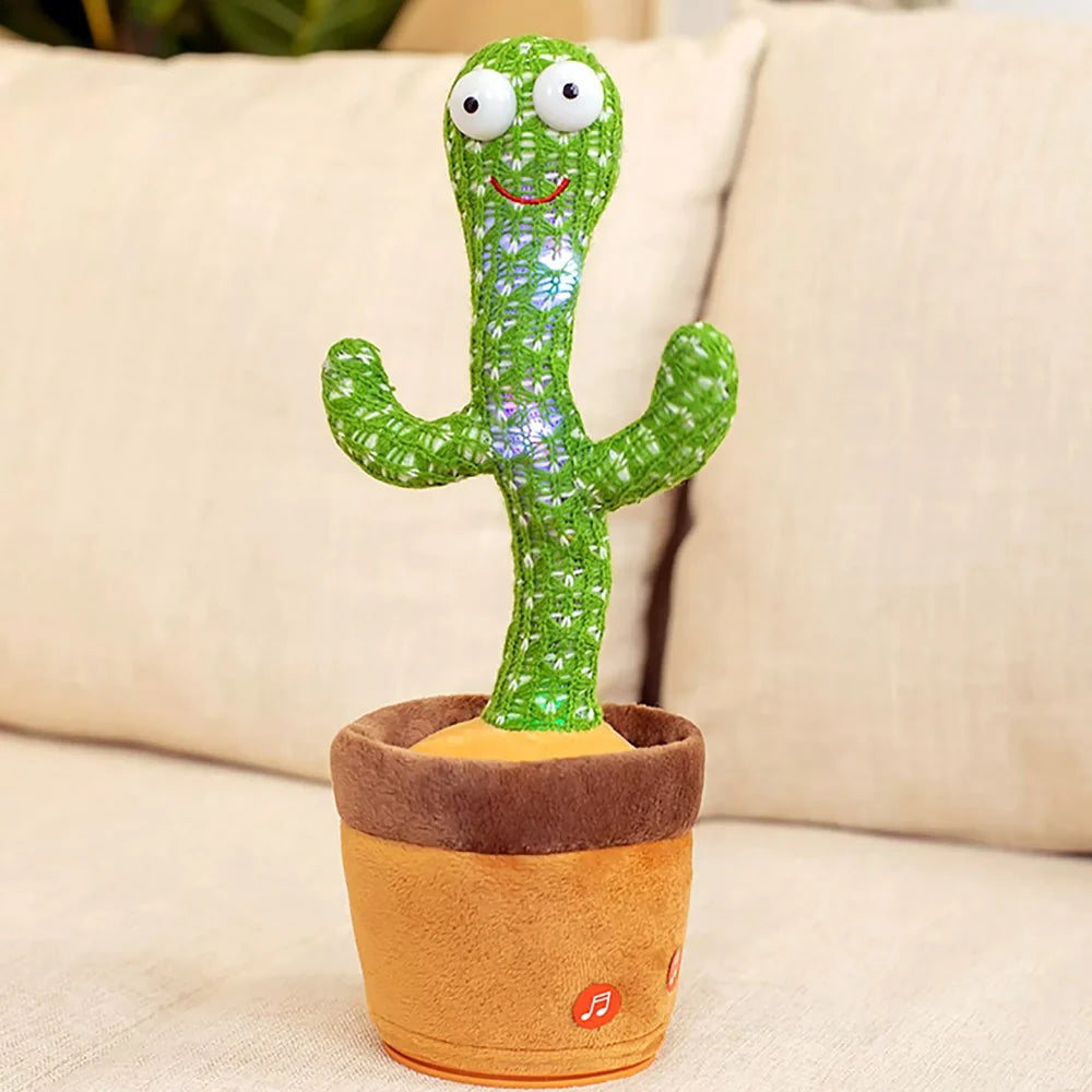 Electronic dancing and singing green knitted cactus toy with big eyes inside a soft brown pot on a white surface.