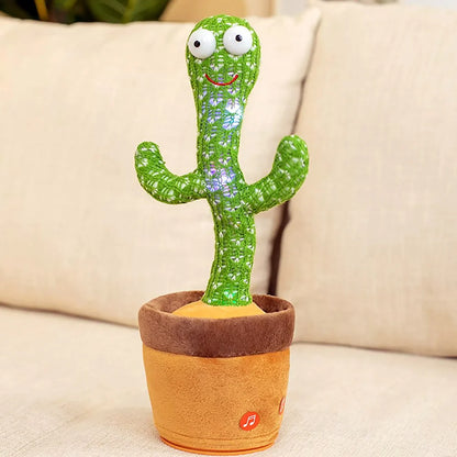 Electronic dancing and singing green knitted cactus toy with big eyes inside a soft brown pot on a white surface.