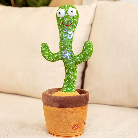 Electronic dancing and singing green knitted cactus toy with big eyes inside a soft brown pot on a white surface.