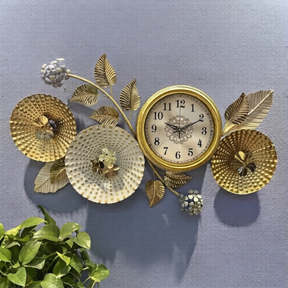 Golden floral branch metal art wall clock featuring textured flower disks and leaves mounted on a textured grey wall.