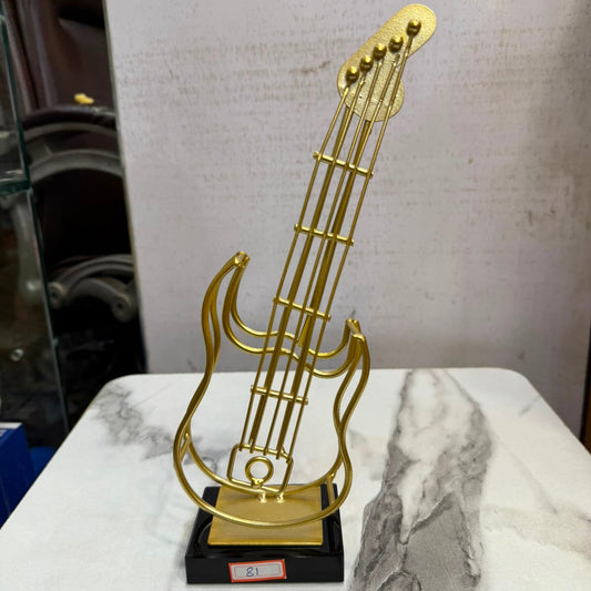 A minimalist gold-toned metal electric guitar showpiece by Gift by Hamza with a sleek black base, perfect for modern home decor.