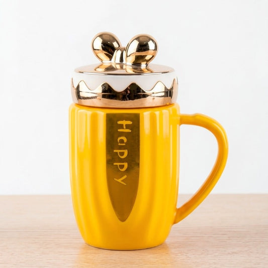 A bright yellow ceramic mug by Gift by Hamza featuring gold "Happy" text, metallic gold accents, and a cute golden bow-shaped lid.