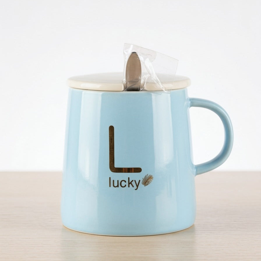 A calming pastel blue ceramic mug by Gift by Hamza with gold "Lucky" text, a ceramic lid, and a included stainless steel spoon.