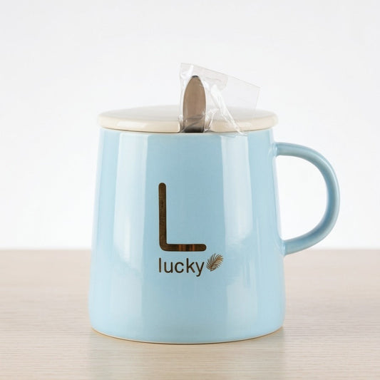 A calming pastel blue ceramic mug by Gift by Hamza with gold "Lucky" text, a ceramic lid, and a included stainless steel spoon.