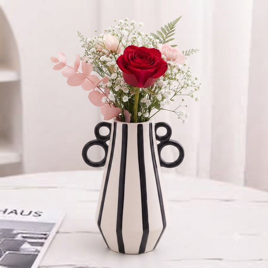 Modern black and white striped ceramic flower vase on a white table.