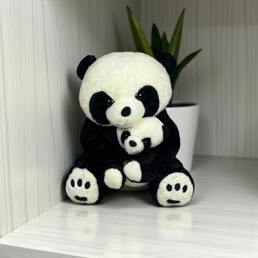A soft, cute mother and baby panda plush toy sitting together against a light background with a decorative plant in a white pot.