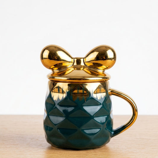 A premium emerald green ceramic mug by Gift by Hamza with a gold textured finish and an iconic golden bow-shaped lid.